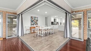 Una cocina moderna con armarios blancos, un comedor con sillas blancas y un ventanal grande.