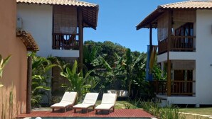 A pool area with lounge chairs and a wooden deck. - Casa Paula (Maraú)