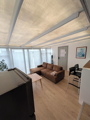 Una sala de estar con un sofá modular, una mesita, un televisor y un sillón.