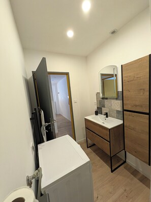 Une salle de bain moderne avec un lavabo blanc, un meuble-lavabo en bois et un miroir au-dessus.