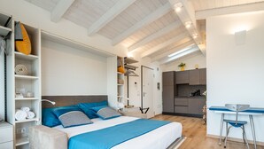 A modern bedroom with a bed, bedside tables, and a built-in desk with a chair. - Le Residenze di Carlà (Cagliari)
