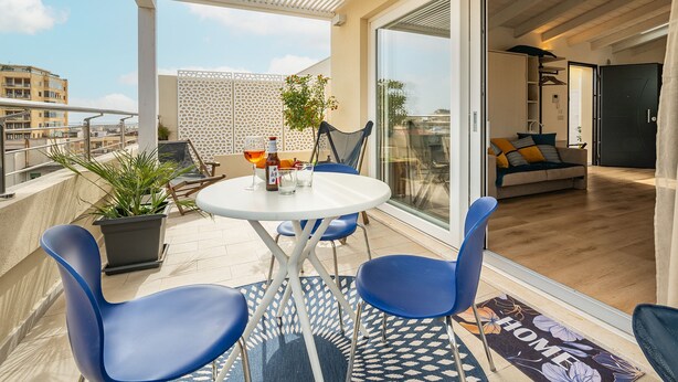 A balcony with a white table, blue chairs, and a potted plant. - Le Residenze di Carlà (Cagliari)
