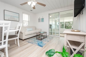 Relax in this stylish living room with a sofa, dining area, and sliding glass door leading to an outdoor space.