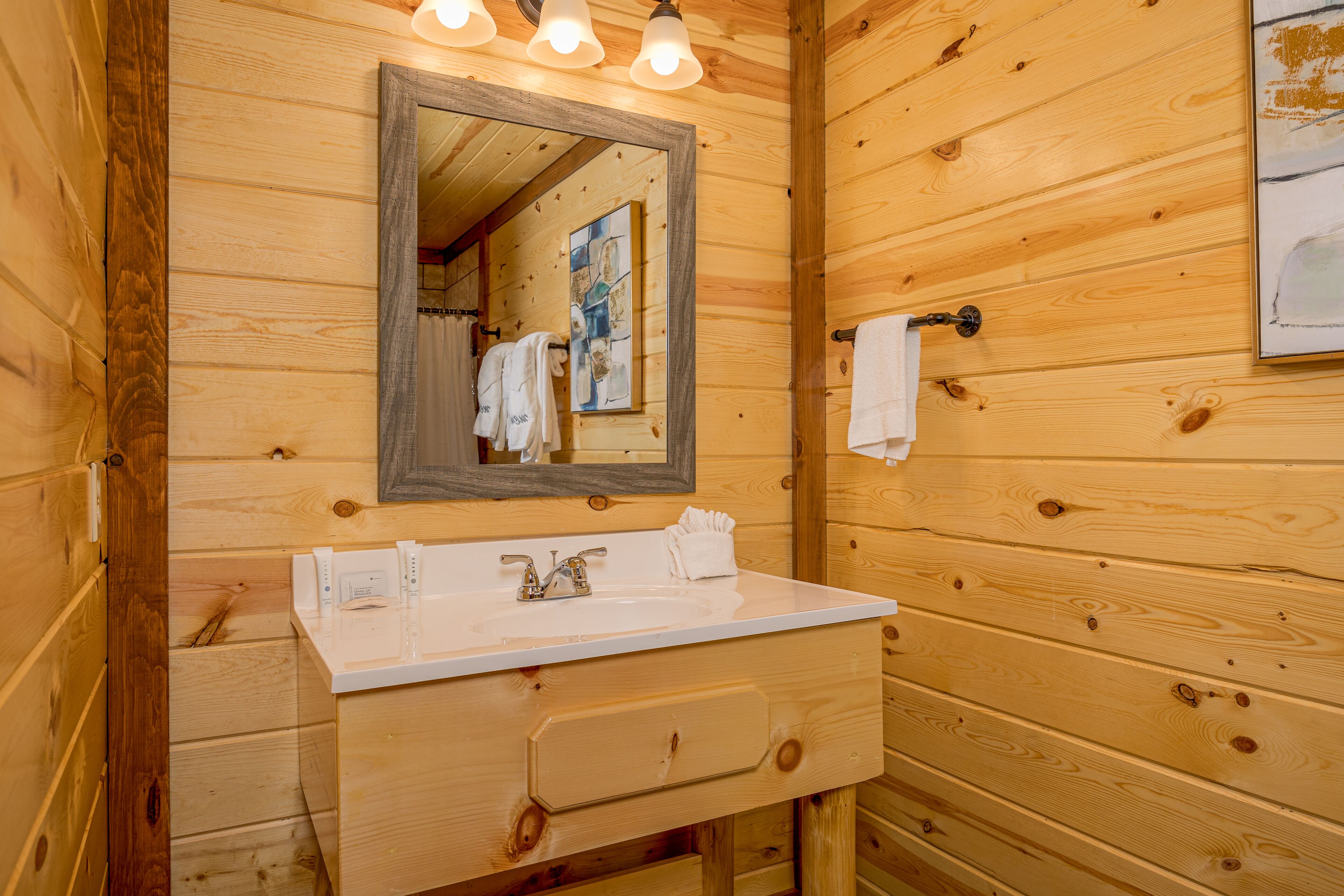 A wooden cabin-style bathroom with a white sink, a mirror, and a towel rack.