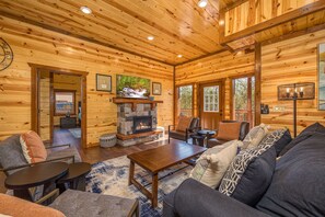 L’intérieur d’un chalet confortable, avec une cheminée en pierre, des murs en bois et un coin salon accueillant.