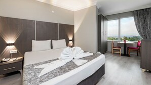 Una habitación de hotel con una cama grande, un escritorio con una silla y vistas al exterior.
