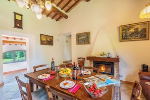 A dining area with a wooden table set for a meal, a fireplace, and framed artwork on the walls.