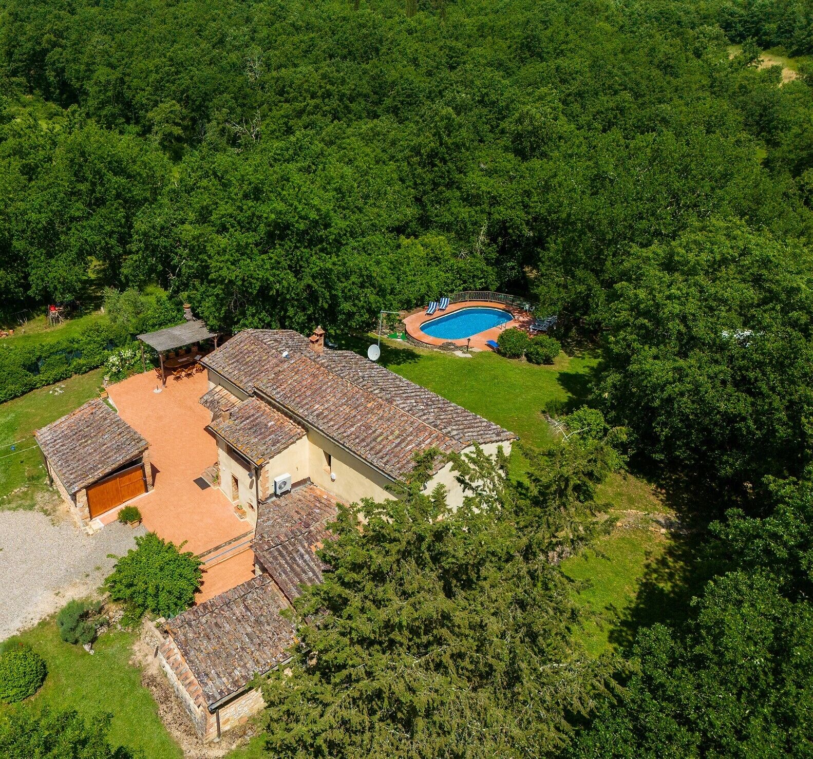 Vue aérienne d’une maison avec une piscine, entourée d’une végétation luxuriante.