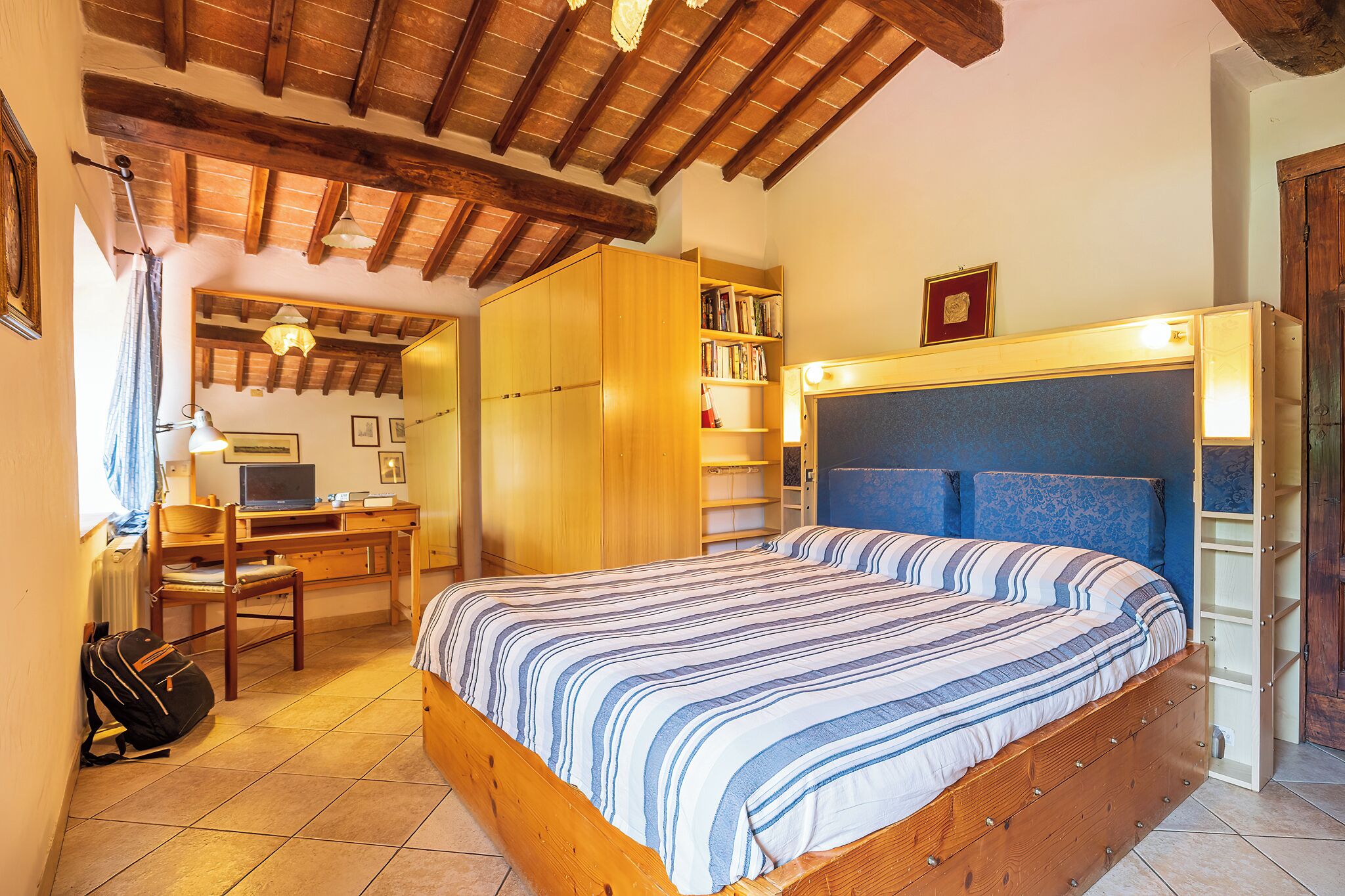 A bedroom with a wooden bed, a desk, and a bookshelf.