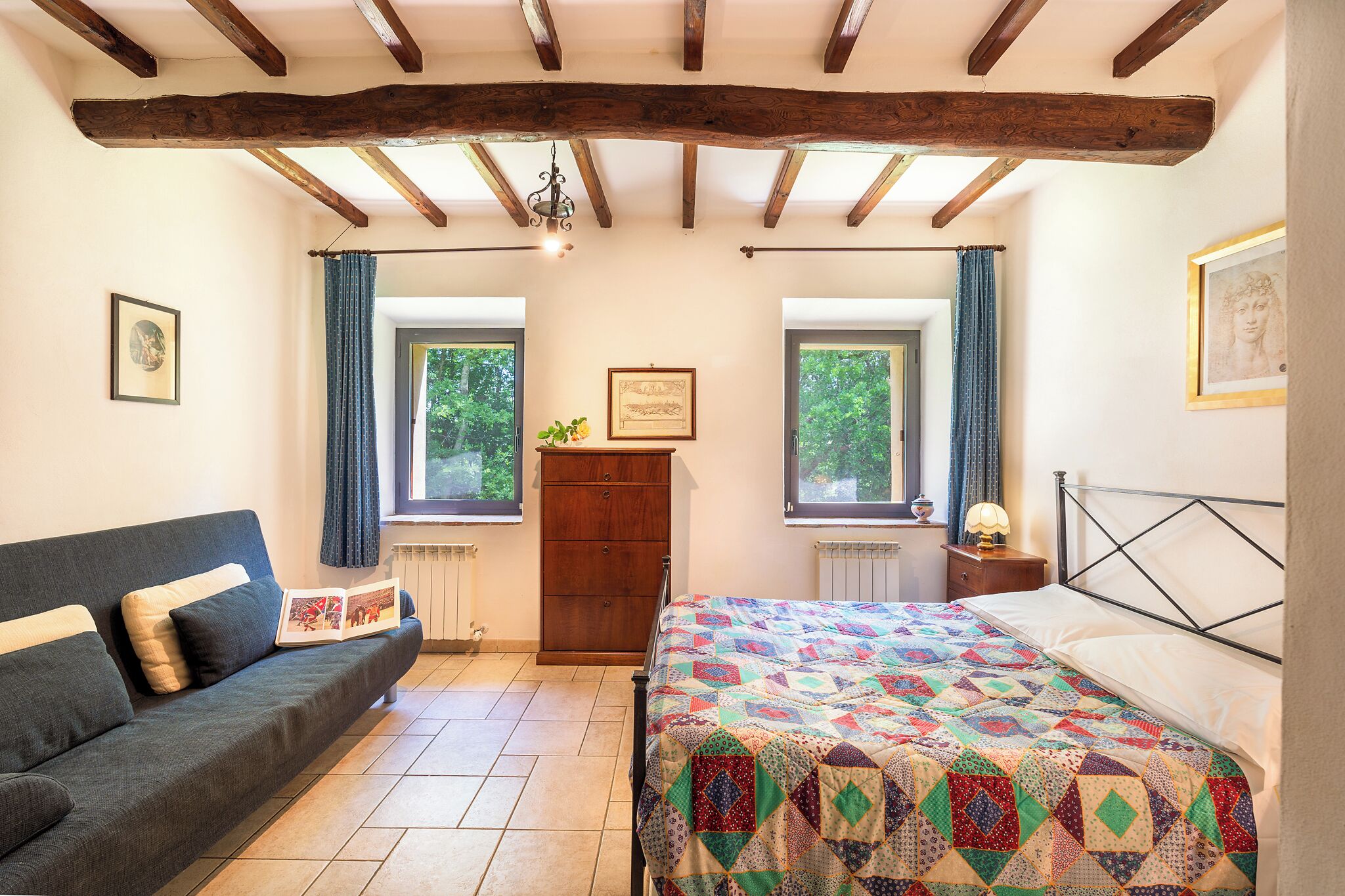 A bedroom with a bed, a sofa, a dresser, and two windows with curtains.