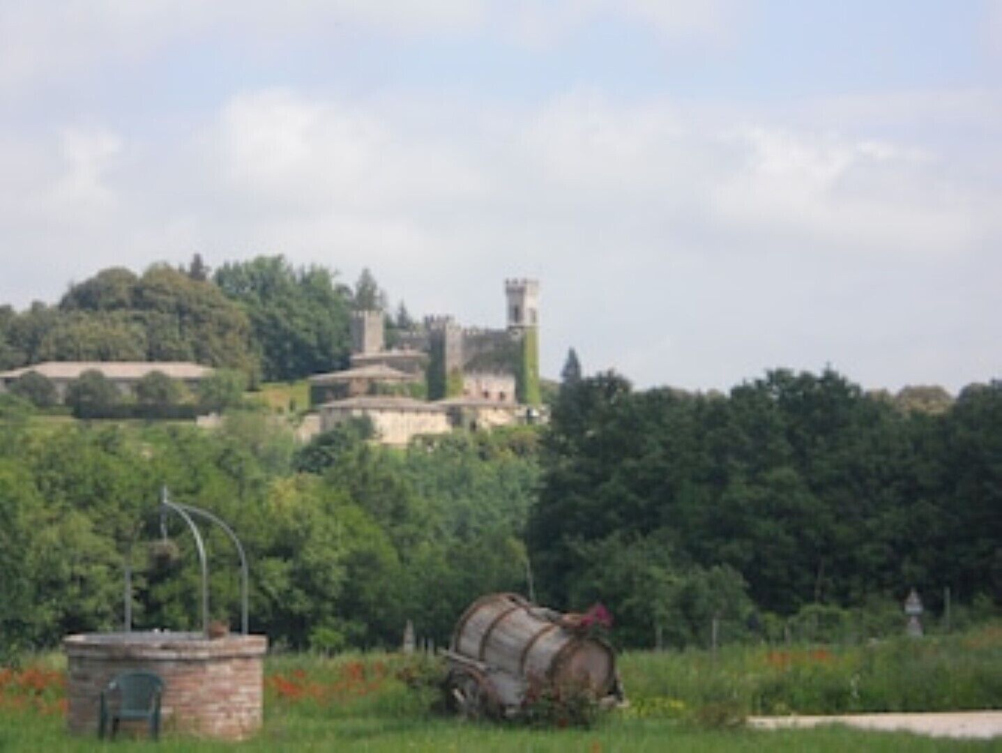 A historic building with a tower, surrounded by lush greenery.