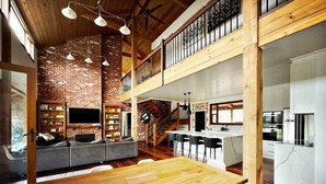 Un loft amplio con una mesa de comedor de madera, una pared de ladrillo y un nivel entre piso.