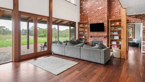 Un salón amplio con un gran sofá seccional gris, una chimenea y una estantería.