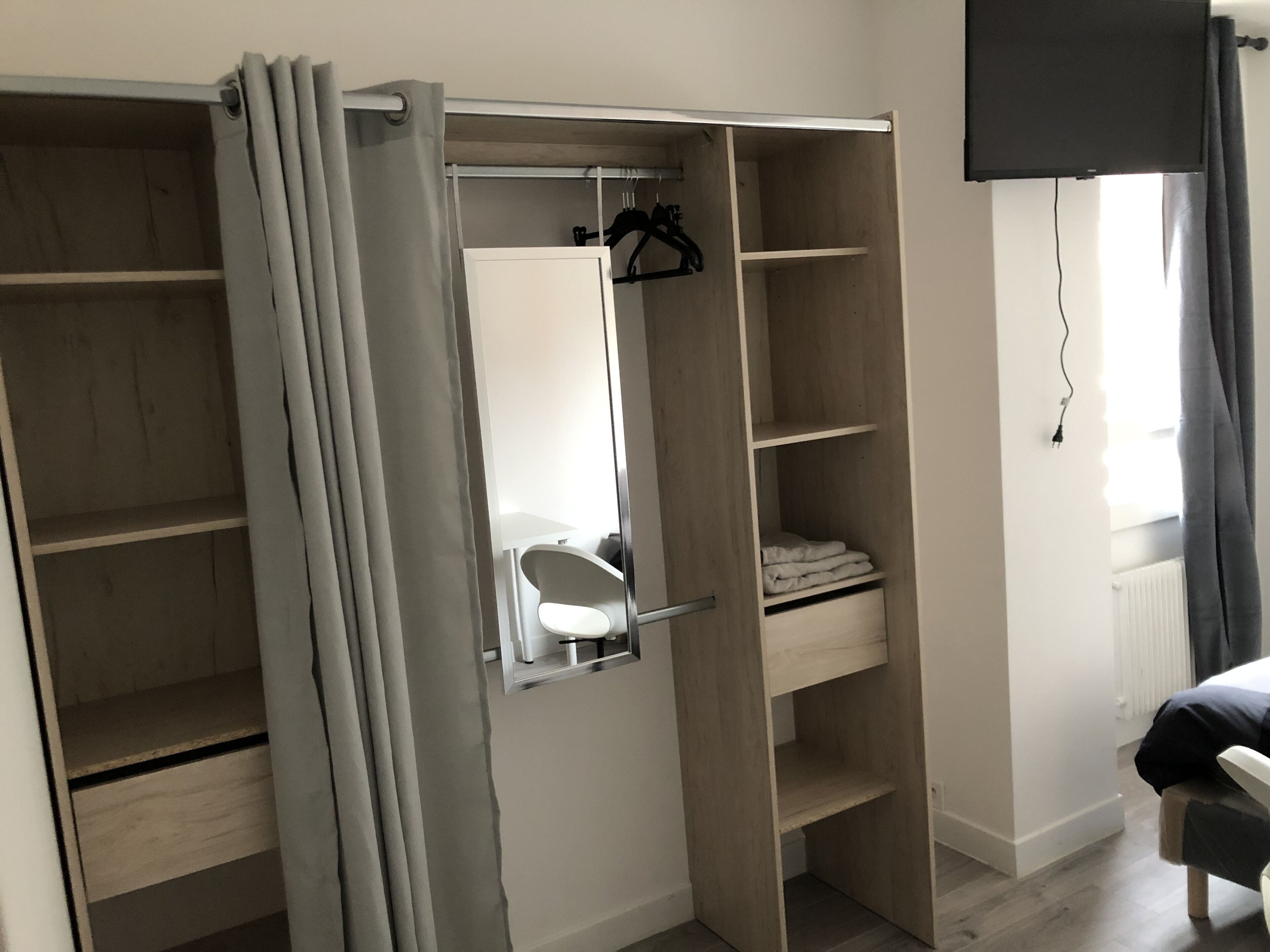 A walk-in closet with open doors, a mirror, and a hanging rack.