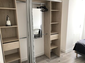 Un dressing avec des portes ouvertes, des étagères et une tringle à vêtements.