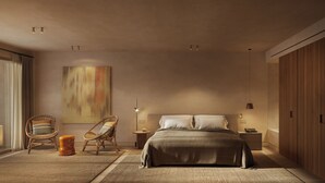 Un dormitorio con una cama, dos sillas, una mesita de noche, una lámpara y un cuadro grande en la pared.