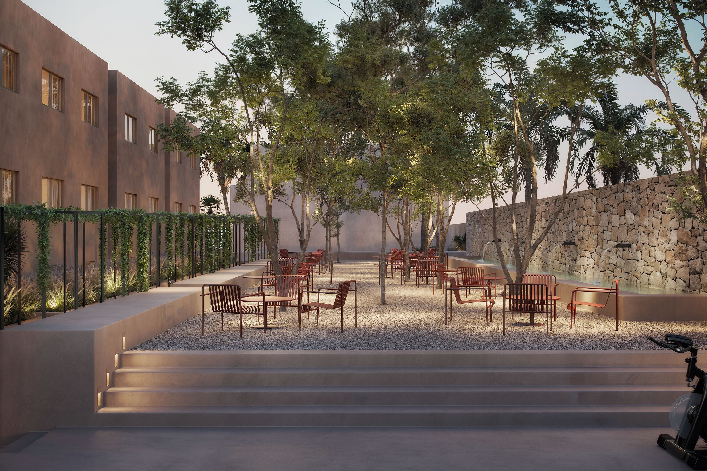 A courtyard with outdoor seating, a stone wall, and a staircase leading to an upper level.