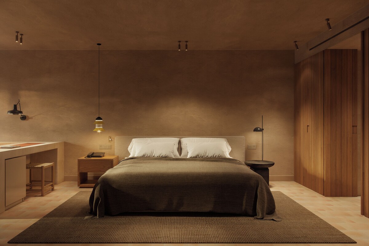 A bedroom with a bed, bedside tables, a desk, and a wardrobe.
