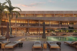 Un hotel de varios niveles con piscina, sillones de descanso y un bar.