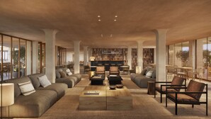 Un amplio salón con sofás, sillones, una mesa de centro y una estantería.