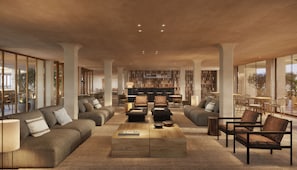 Un amplio salón con sofás, sillones, una mesa de centro y una estantería.