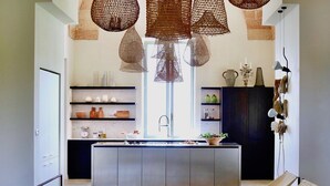 Una cucina moderna con isola centrale, luci a sospensione e scaffalature a giorno.