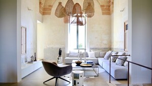 Un ampio soggiorno con soffitto ad arco, un divano moderno, una poltrona contemporanea e un tavolino da caffè.