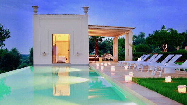 Area piscina con piscina, sedie a sdraio e zona relax coperta.