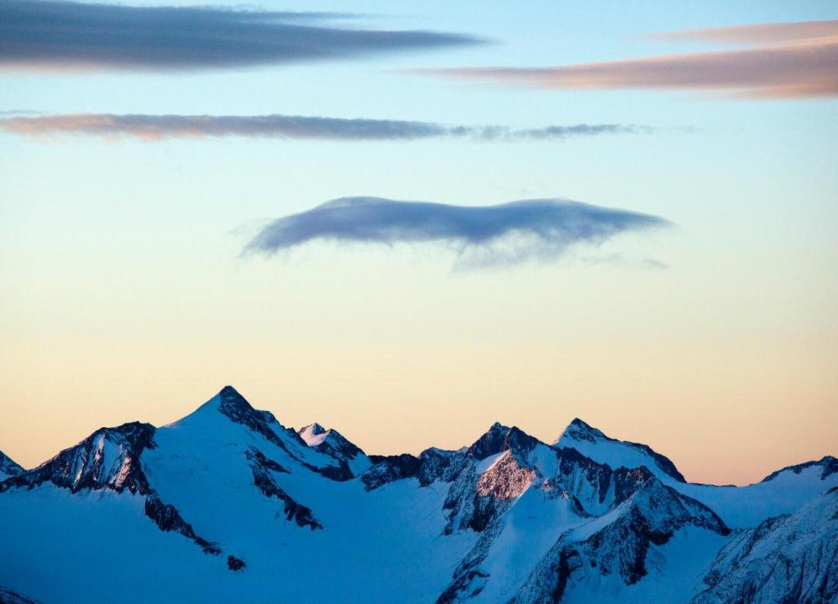 Cordilheira com picos nevados e céu claro.