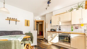 Una cocina moderna con horno empotrado, un comedor con mesa y sillas, y una sala de estar con sofá.