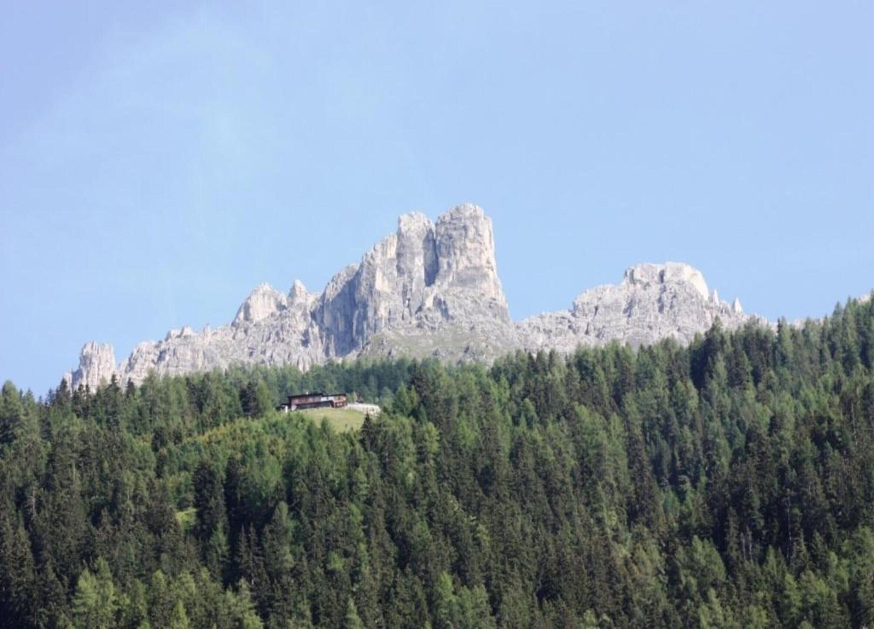 Un paysage montagneux avec une colline boisée et un bâtiment au sommet.