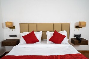 A hotel room with a bed, two nightstands, a telephone, and wall-mounted lamps. - VAARSA (Alibag)