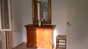 A bedroom with a bed, a dresser, a mirror, and a door. - In the heart of the Grand Luberon, a SWIMMING POOL, a QUIET, comfortable home. (Castellet-en-Luberon)