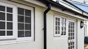 A building with white exterior walls, multiple windows with white frames, and a black gutter running along the roof edge. - 1 bedroom accommodation in Cemaes Bay (Cemaes Bay)
