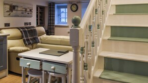 A cozy living room with a sofa, a small table, and a staircase. - 1 bedroom accommodation in Cemaes Bay (Cemaes Bay)