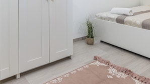 A bedroom with a bed, a wardrobe, a potted plant, and a light fixture. - Real Apartments Kertész II. (Budapest)
