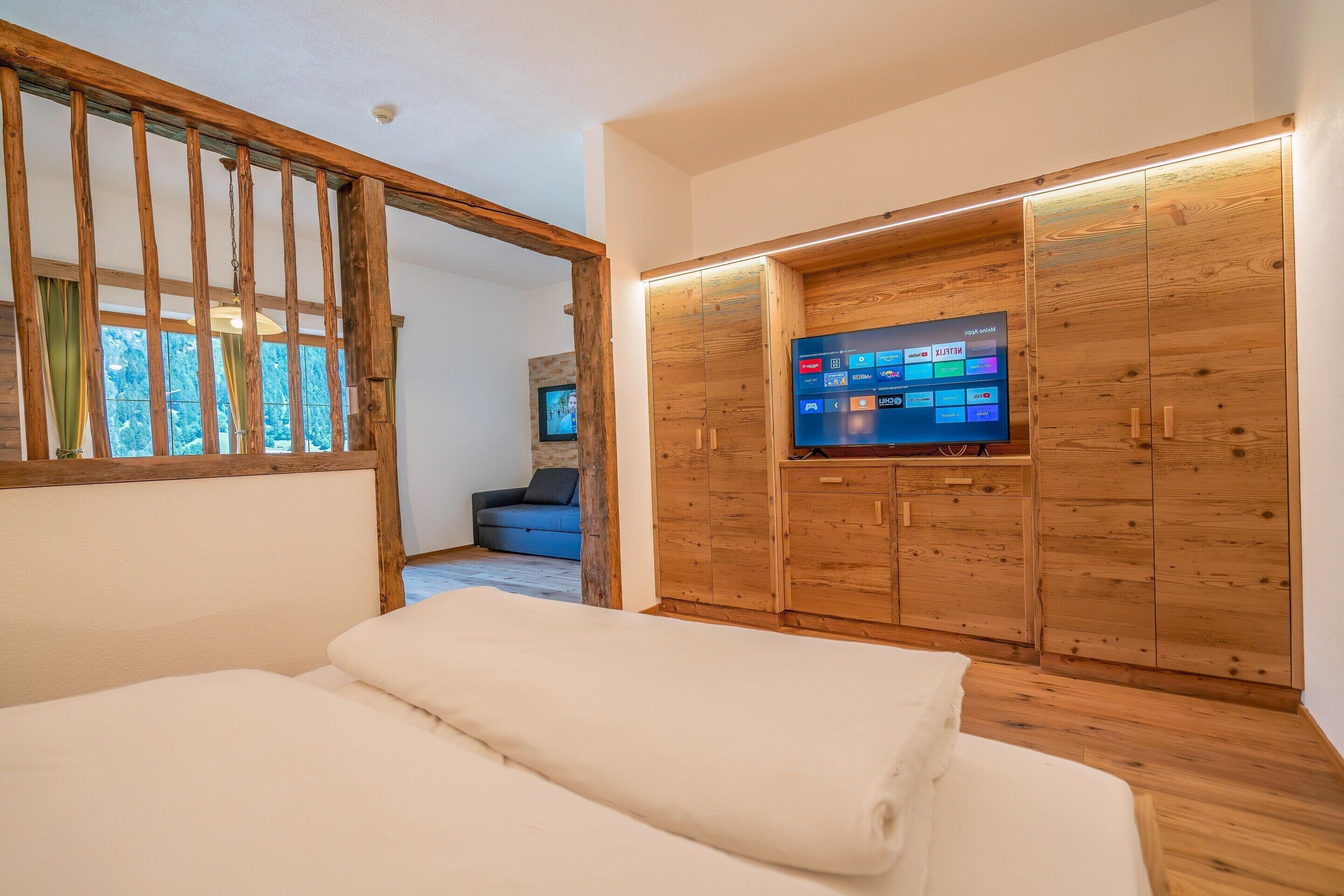 A bedroom with a bed, wooden wardrobe, and a television.