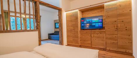 A bedroom with a bed, wooden wardrobe, and a television.