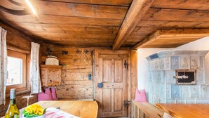 A rustic wooden interior with a wooden door, a bench, and a table with a bottle and flowers. - Spacious Holiday Home With Sauna (Fuegenberg)