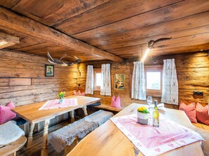 Ein rustikales Holzinnere mit Holztischen und -bänken, gerahmten Bildern an den Wänden und einer gemütlichen Atmosphäre.