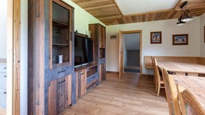 A rustic interior with wooden floors, a dining area, and a television set.