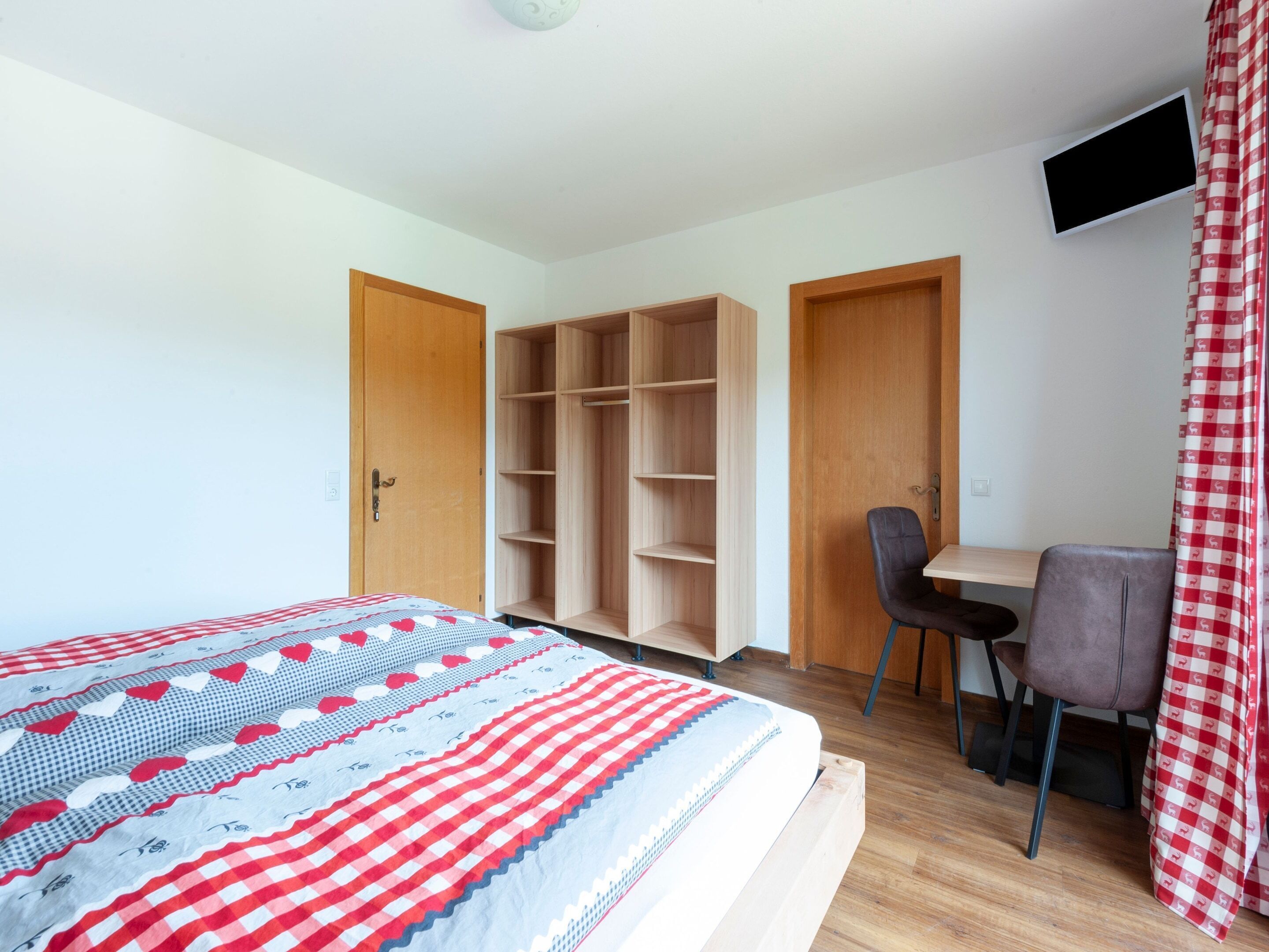 Een slaapkamer met een bed, een bureau en twee kledingkasten.