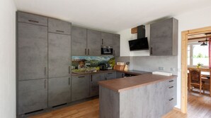 A modern kitchen with grey cabinets, a wooden island, and a built-in microwave.