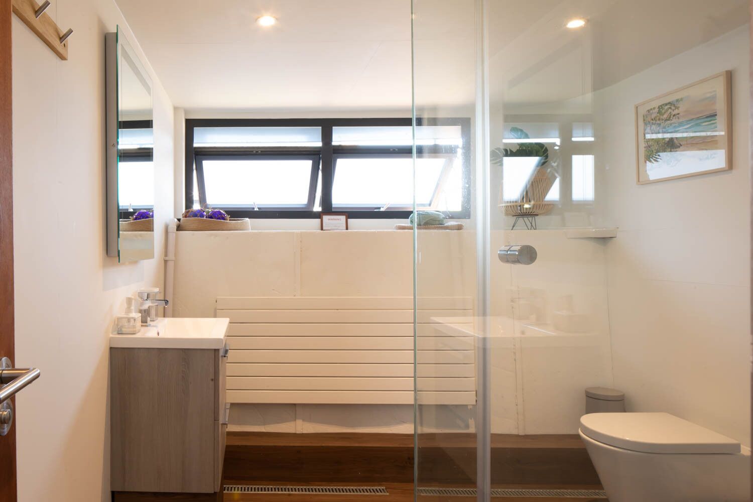 A modern bathroom with a glass shower enclosure, a white sink, and a toilet.