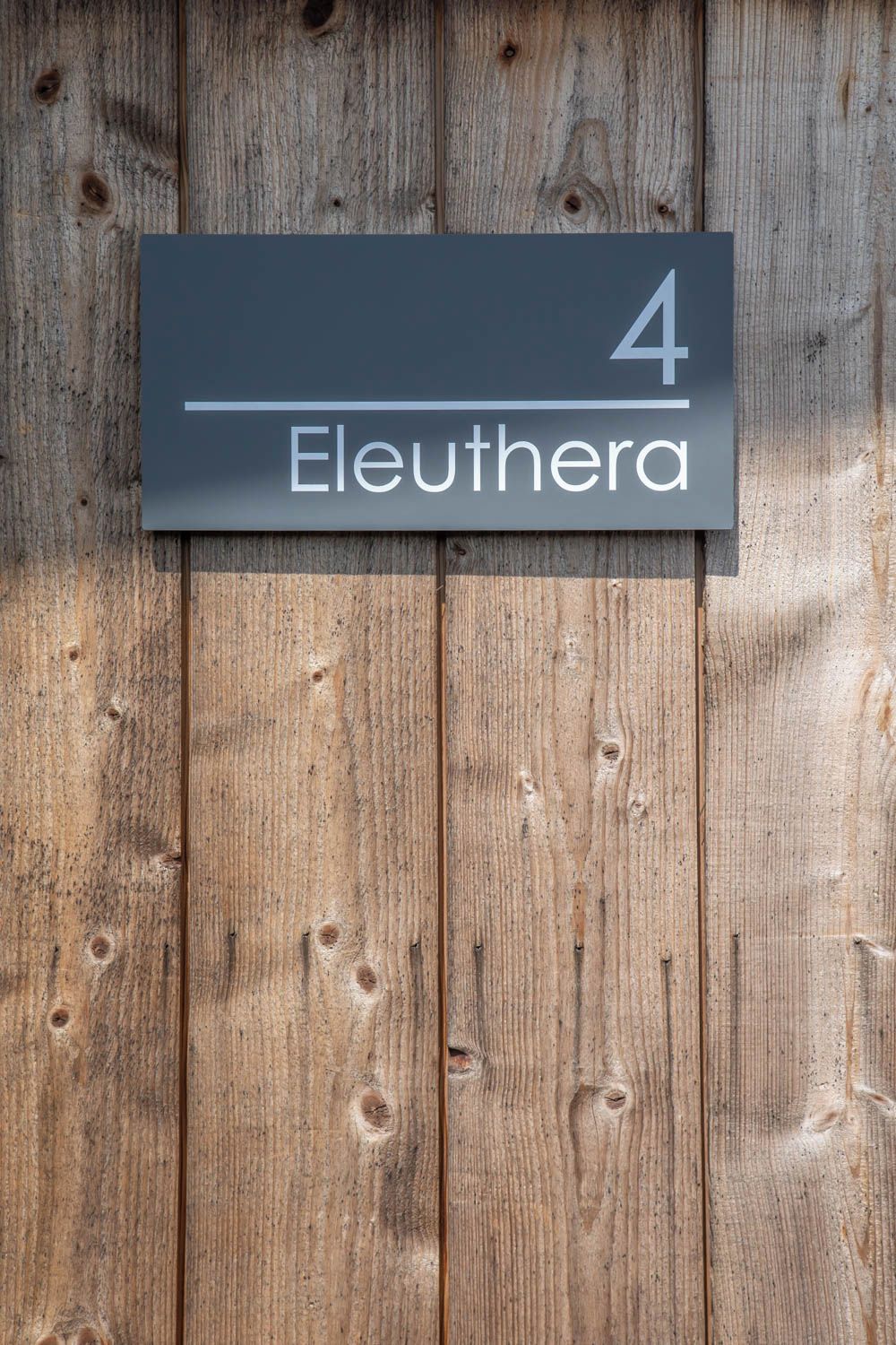 Un letrero con el número 4 y la palabra 'Eleuthera' sobre un fondo de madera.