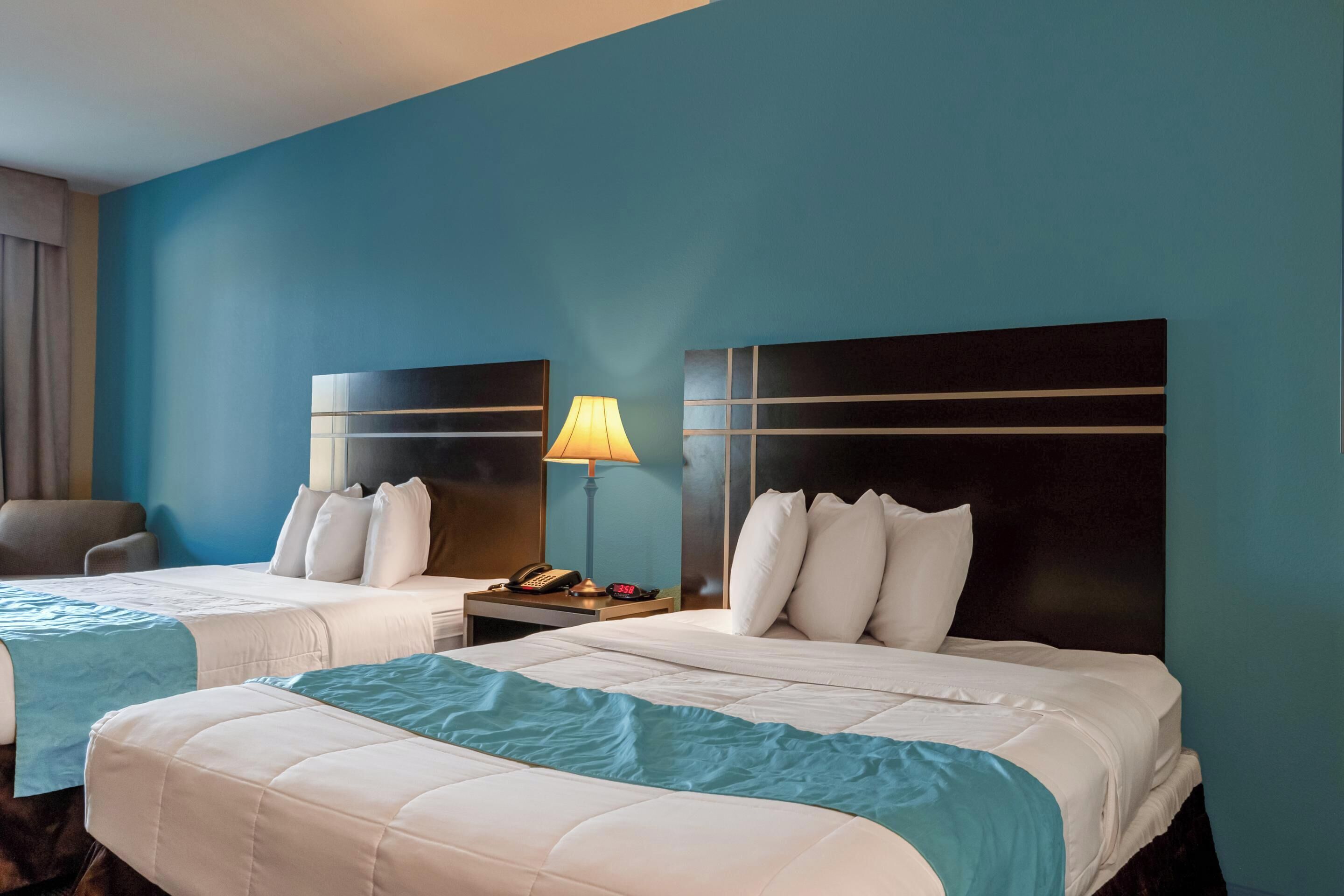 Ein Hotelzimmer mit zwei Betten, einem Nachttisch mit Lampe und einem Sessel.