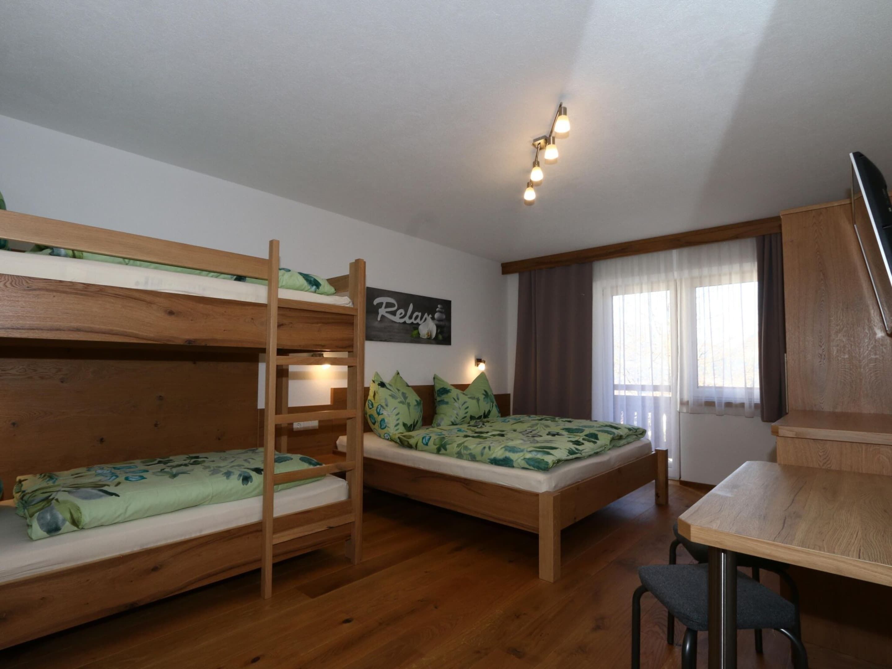 Une chambre avec un lit superposé, une table en bois et un téléviseur.