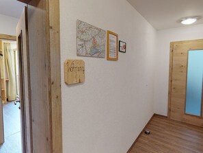 Un passadís amb una porta de fusta, un mapa i un cartell de benvinguda a la paret.