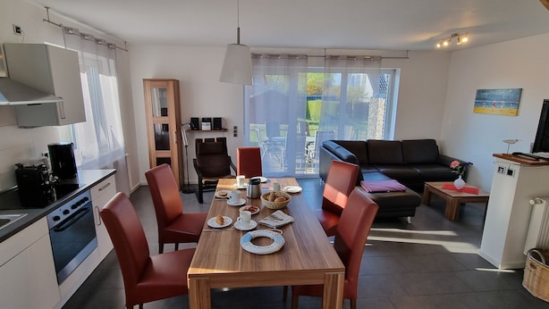 A modern kitchen with a dining area, a sofa, and a TV.