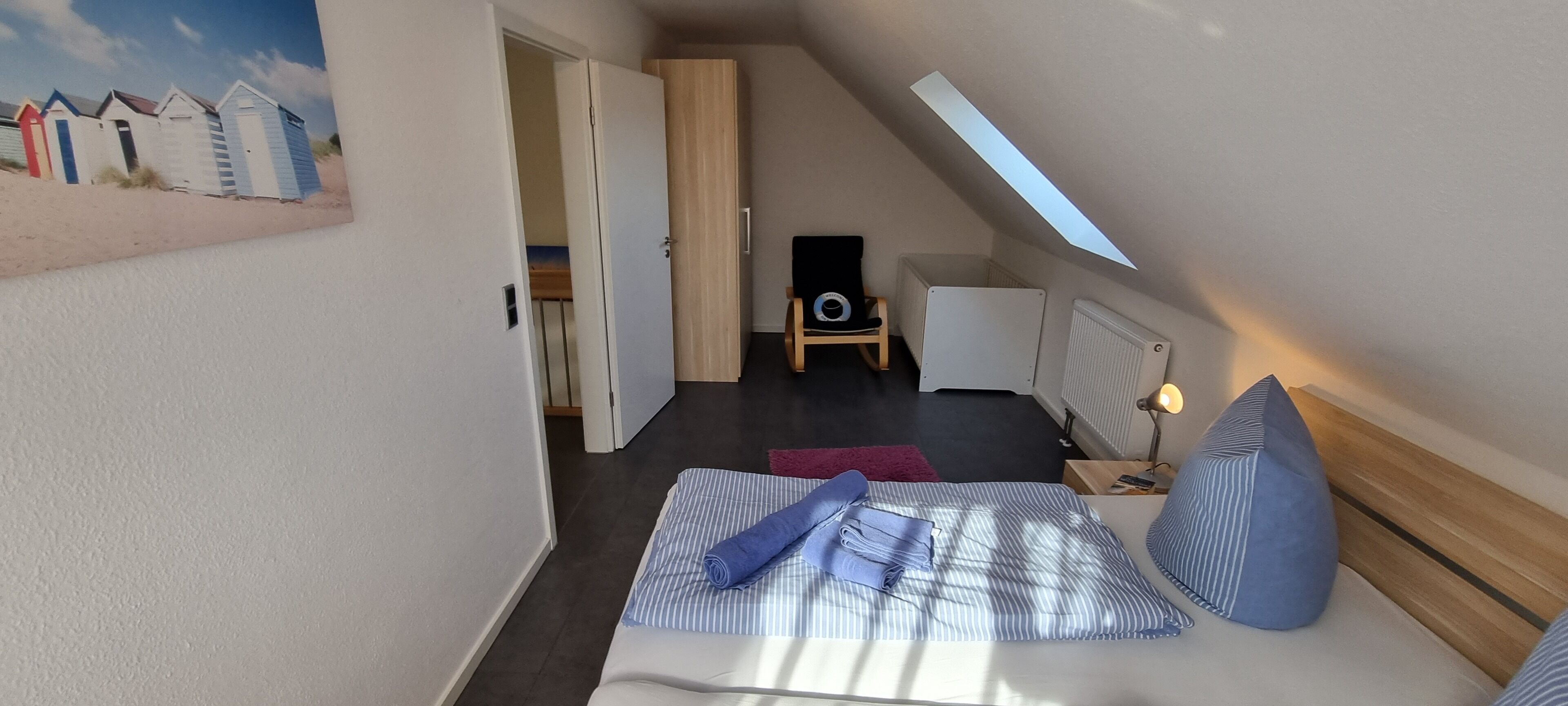 A bedroom with a bed, a chair, a radiator, and a skylight.
